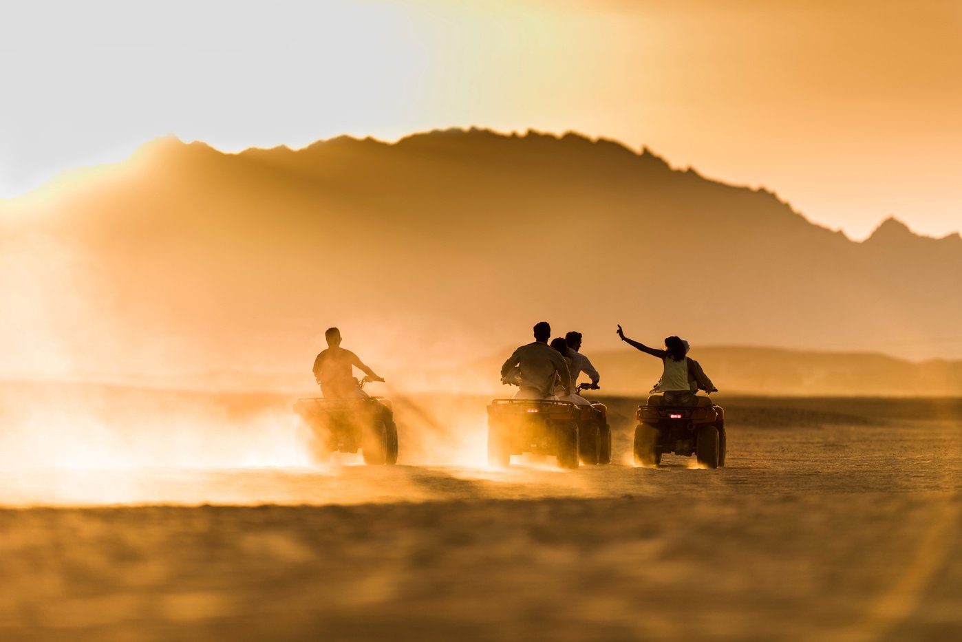 Driving quad bikes at sunset.